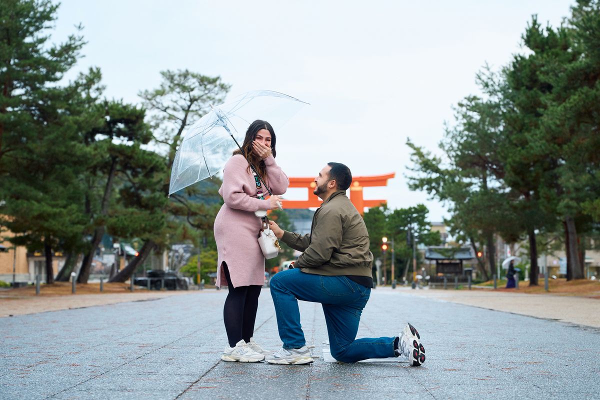 Hand over her mouth as Erik proposes beneath the torii gate